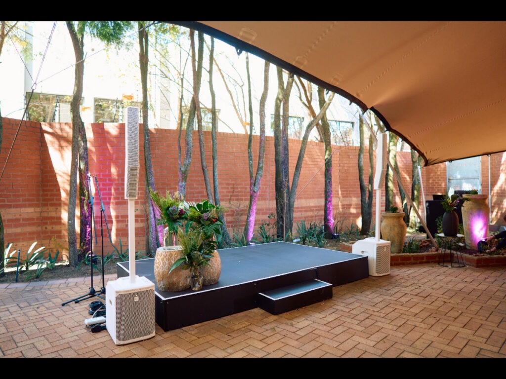 Small stage with potted floral arrangements under trees