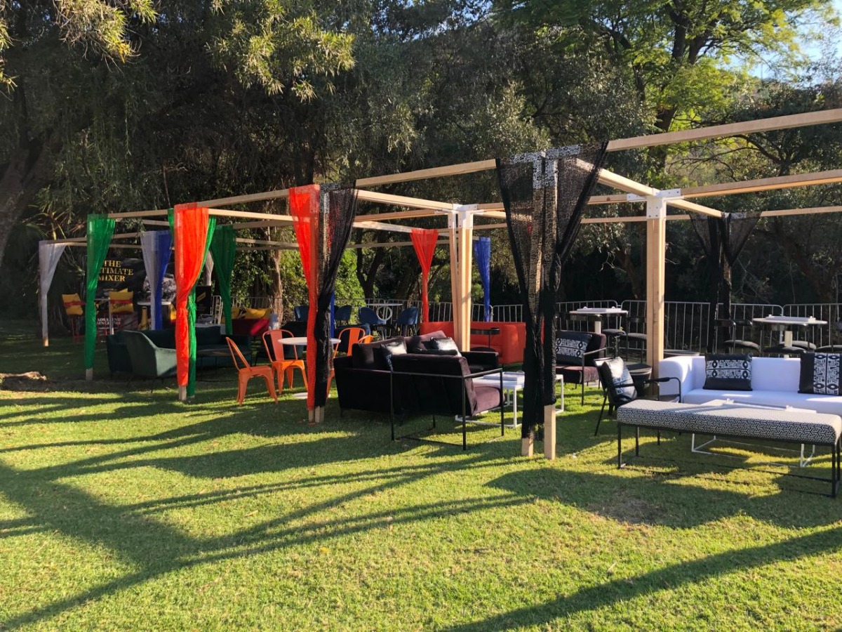 Bright outdoor lounge setup with colourful draping and black furniture