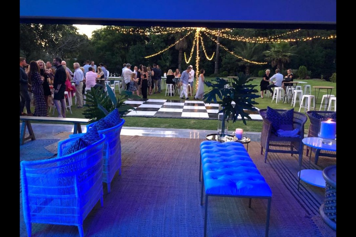 Outdoor garden lounge setup with hanging fairy lights and checkerboard flooring