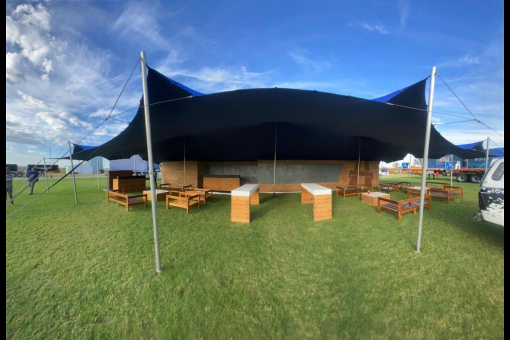 Outdoor exhibition lounge with stretch tent and wooden tables