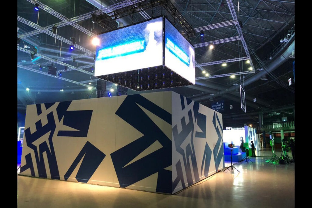 Modern cube-shaped expo booth with branded blue pattern
