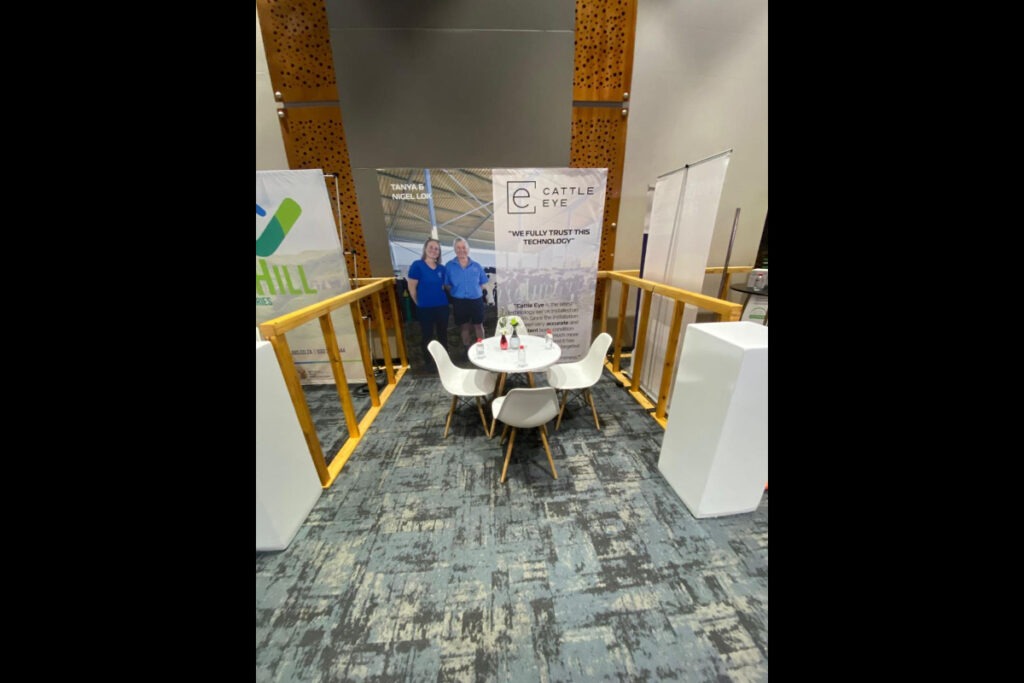 Compact expo booth with white chairs and printed graphic backdrop